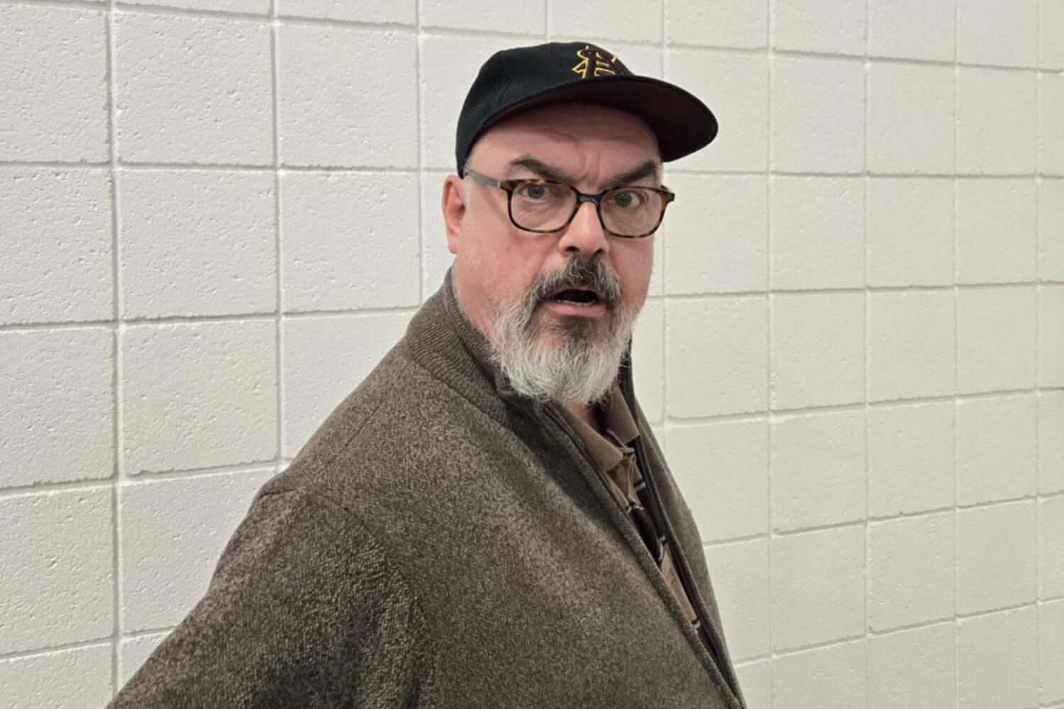 photo of Shawn Bramanti wearing a hat and sweatshirt in front of a tiled wall